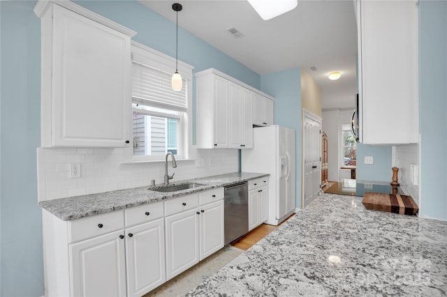 kitchen with stainless steel dishwasher, white refrigerator with ice dispenser, white cabinets, a sink, and decorative backsplash