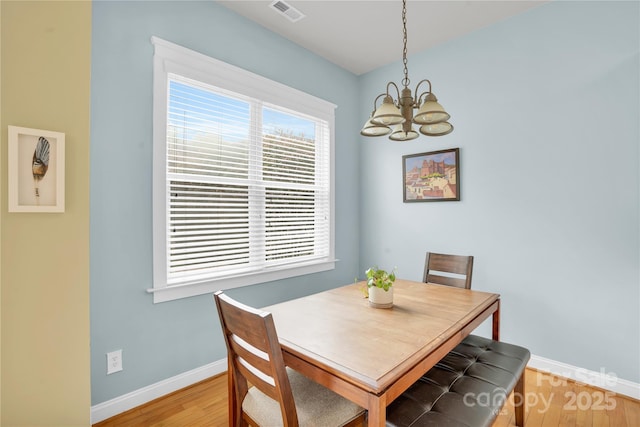 dining room with a chandelier, light wood finished floors, visible vents, and baseboards