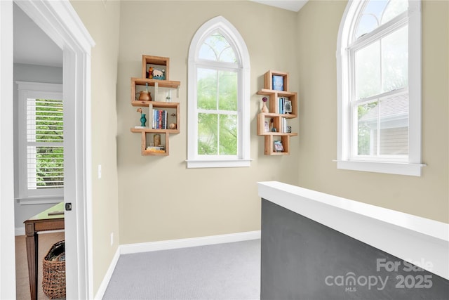 hallway featuring carpet flooring and baseboards
