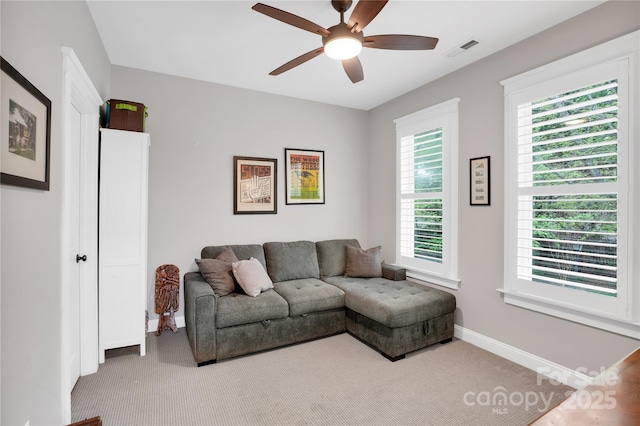 carpeted living room with a wealth of natural light, visible vents, baseboards, and ceiling fan