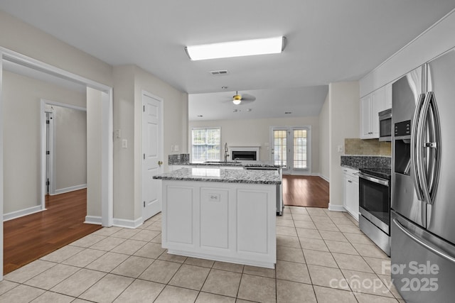 kitchen featuring light tile patterned flooring, a fireplace, a sink, and appliances with stainless steel finishes