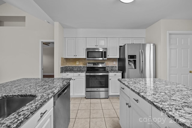 kitchen with tasteful backsplash, white cabinetry, light stone counters, and appliances with stainless steel finishes