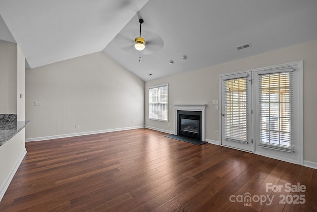 unfurnished living room with a glass covered fireplace, dark wood-type flooring, visible vents, and a ceiling fan