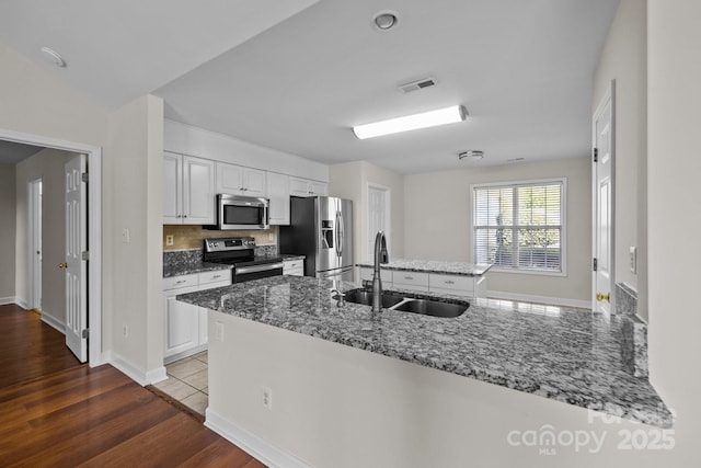 kitchen with white cabinetry, visible vents, stone countertops, appliances with stainless steel finishes, and a sink