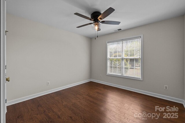 unfurnished room featuring dark wood-type flooring, visible vents, baseboards, and ceiling fan