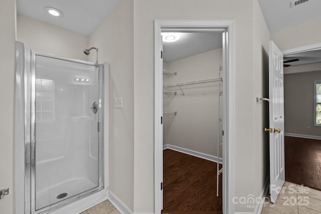 bathroom featuring a stall shower, baseboards, a spacious closet, and visible vents