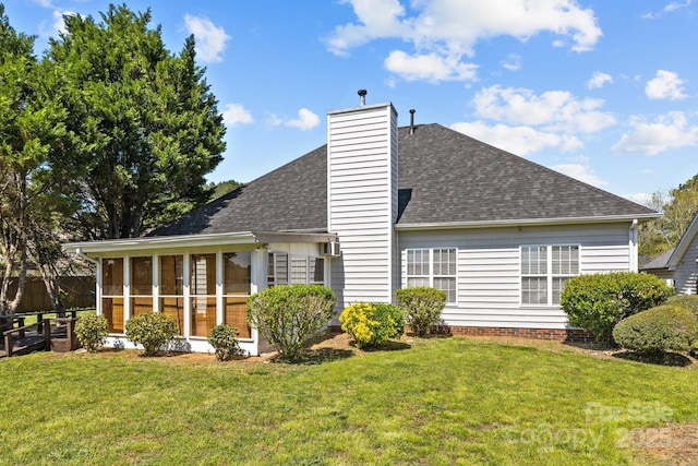 rear view of house with a yard, a shingled roof, a sunroom, and a chimney