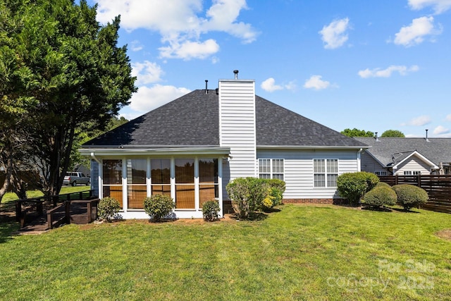 rear view of property featuring a sunroom, a yard, a chimney, fence, and roof with shingles
