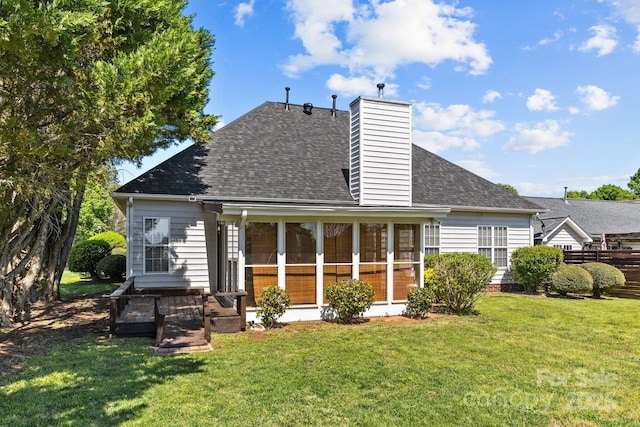 back of property featuring roof with shingles, a chimney, a sunroom, and a lawn