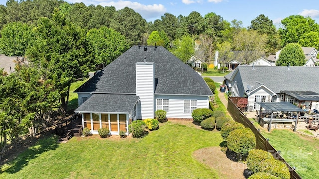 rear view of house with a yard, a chimney, and roof with shingles
