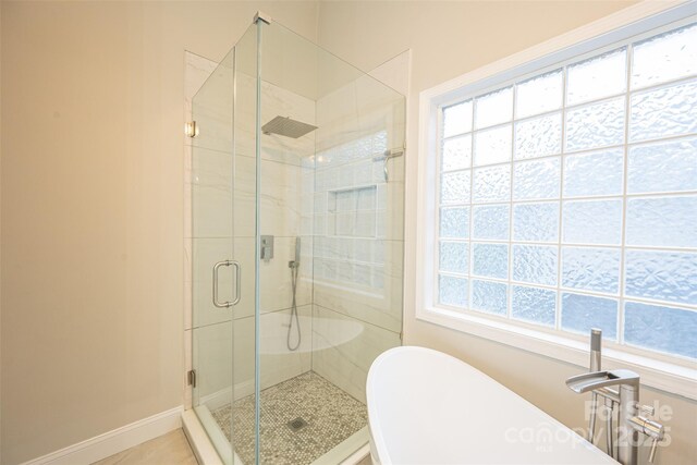 bathroom with baseboards, a freestanding tub, and a stall shower