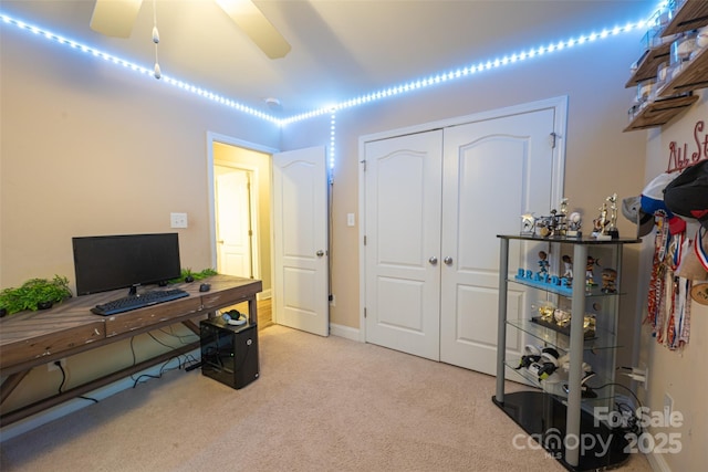 carpeted home office with ceiling fan and baseboards