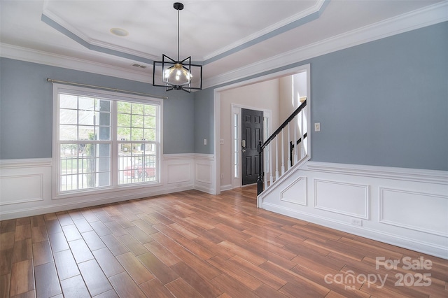 interior space featuring a wainscoted wall, wood finished floors, and a chandelier