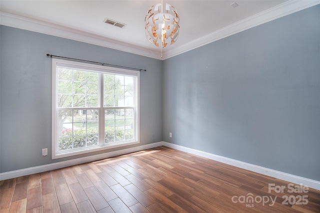 unfurnished room featuring an inviting chandelier, wood finished floors, visible vents, ornamental molding, and baseboards