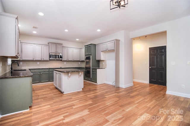 kitchen featuring a sink, decorative backsplash, stainless steel appliances, baseboards, and a kitchen island