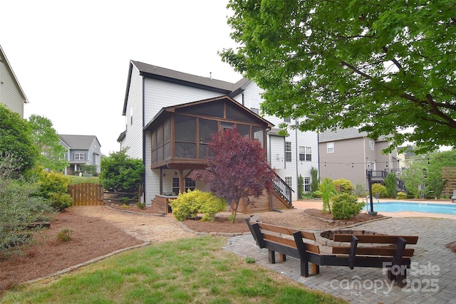 back of house with fence, an outdoor pool, a sunroom, and stairway