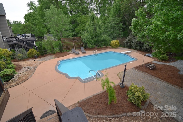 outdoor pool with fence, a diving board, and a patio