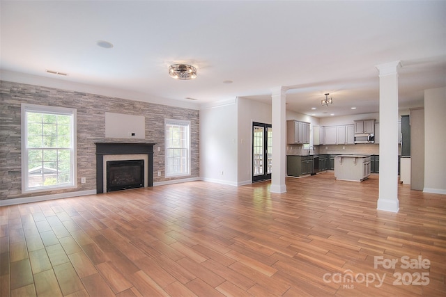 unfurnished living room with decorative columns, baseboards, and a healthy amount of sunlight