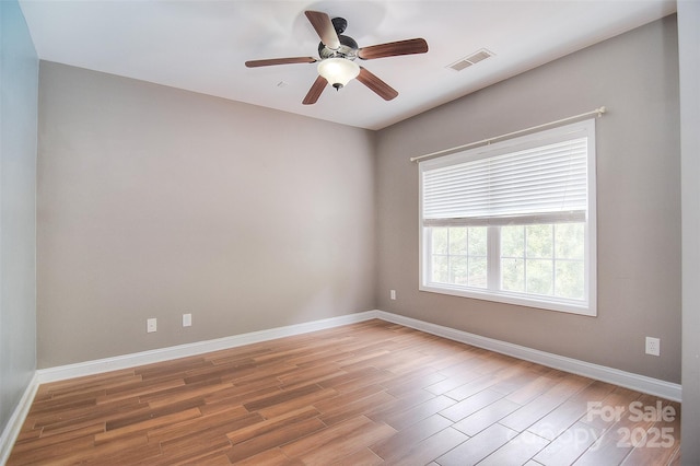 spare room with ceiling fan, baseboards, wood finished floors, and visible vents