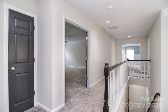 corridor featuring carpet floors, an upstairs landing, visible vents, and baseboards