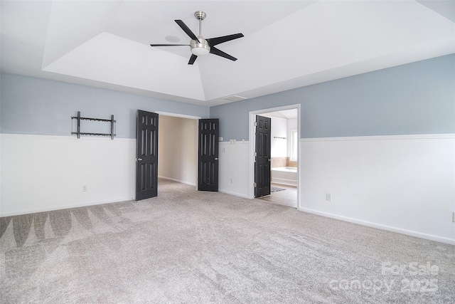 unfurnished bedroom featuring carpet flooring, ensuite bathroom, visible vents, baseboards, and ceiling fan