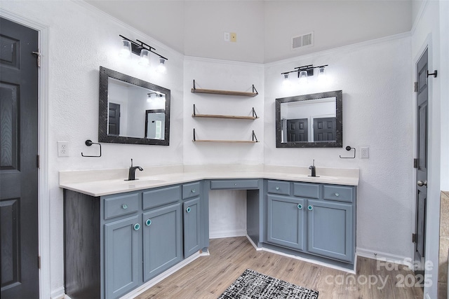 bathroom with double vanity, wood finished floors, visible vents, and a sink