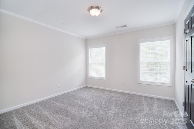 spare room featuring carpet floors, ornamental molding, visible vents, and baseboards