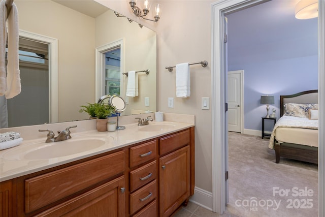 ensuite bathroom with a sink, baseboards, ensuite bath, and double vanity