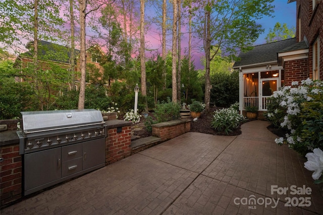 patio terrace at dusk featuring a grill and area for grilling