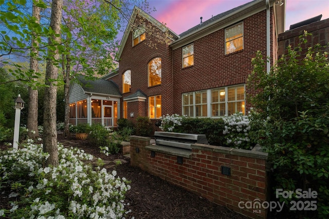rear view of house with brick siding and a sunroom