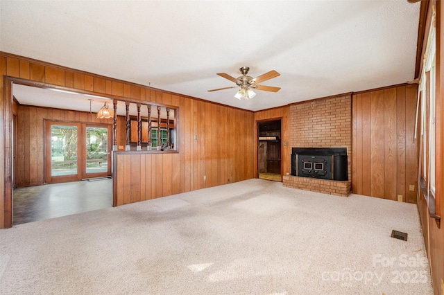 2415 Hargette Rd, Monroe, NC 28112 - unfurnished living room featuring a wood stove, ceiling fan, visible vents, carpet floors, and wood walls