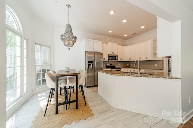 108 Tall Oak Dr, Mooresville, NC 28117 - kitchen with crown molding, a chandelier, dark stone countertops, stainless steel appliances, and decorative backsplash