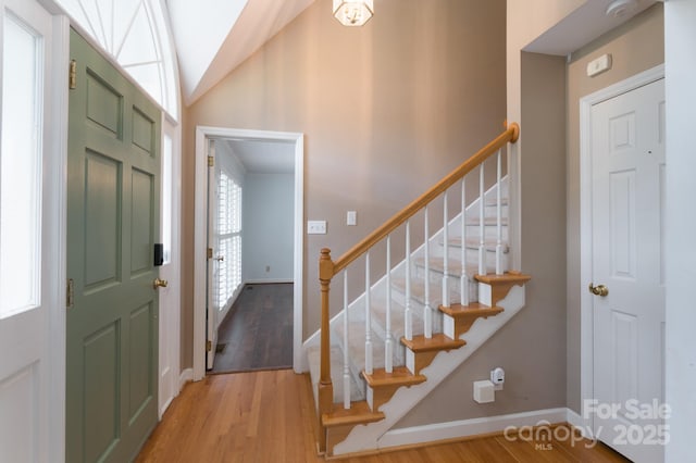 entryway featuring stairs, wood finished floors, baseboards, and lofted ceiling