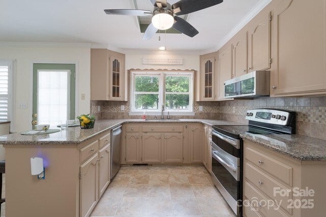kitchen with stainless steel appliances, a sink, a peninsula, glass insert cabinets, and backsplash