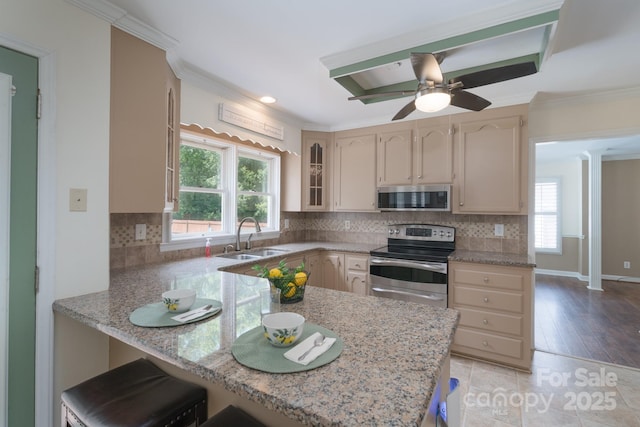 kitchen with stainless steel appliances, a sink, a peninsula, ornamental molding, and decorative backsplash