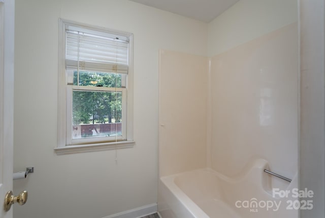 bathroom with a bath, a shower, and baseboards