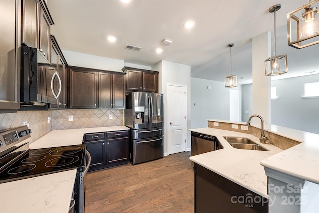 kitchen with visible vents, dark wood-type flooring, a sink, backsplash, and stainless steel appliances