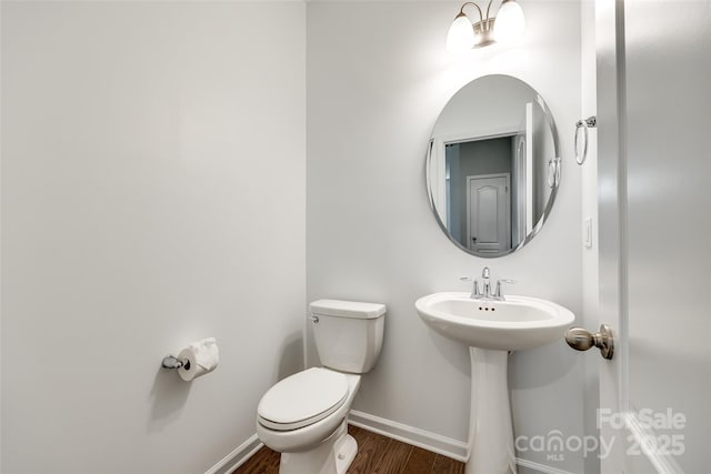 bathroom featuring baseboards, a sink, wood finished floors, and toilet