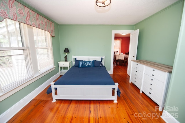 bedroom featuring baseboards, crown molding, and wood finished floors