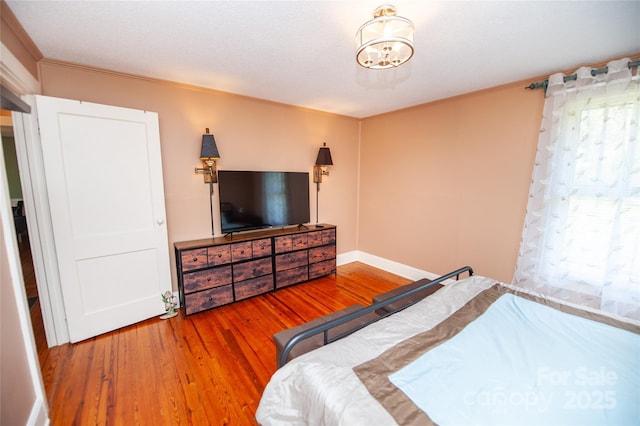 bedroom featuring ornamental molding, an inviting chandelier, and wood finished floors