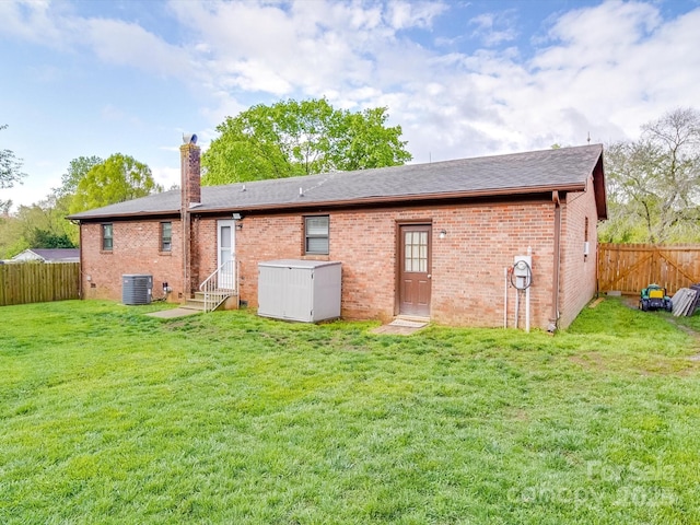 1315 Holshouser Rd, Rockwell, NC 28138 - rear view of house with a fenced backyard, a lawn, brick siding, a chimney, and central AC unit