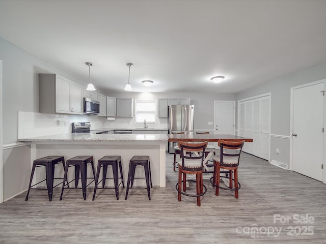 1315 Holshouser Rd, Rockwell, NC 28138 - kitchen featuring a kitchen breakfast bar, a peninsula, visible vents, appliances with stainless steel finishes, and light wood finished floors