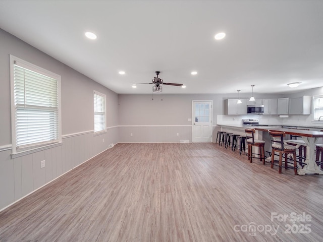 1315 Holshouser Rd, Rockwell, NC 28138 - unfurnished living room with a healthy amount of sunlight, light wood finished floors, wainscoting, and ceiling fan