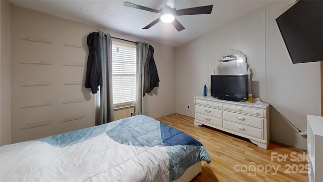 bedroom featuring light wood-style flooring, ceiling fan, and a textured ceiling