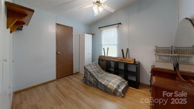 sitting room with baseboards, ceiling fan, a textured ceiling, light wood finished floors, and vaulted ceiling
