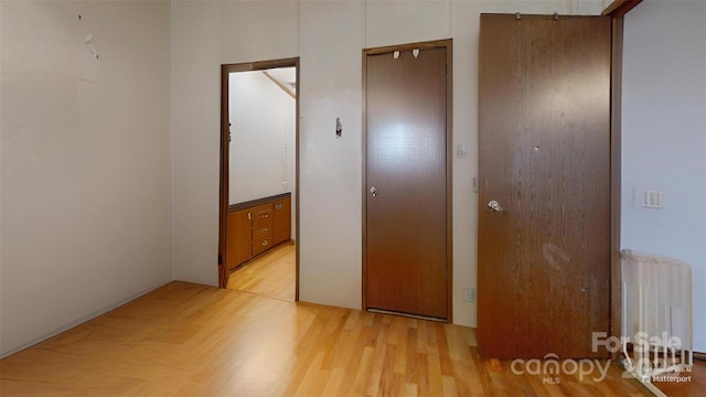 unfurnished bedroom featuring radiator heating unit and light wood-type flooring