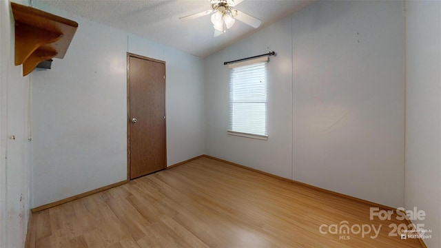 unfurnished bedroom with light wood-style floors, a textured ceiling, vaulted ceiling, and a ceiling fan