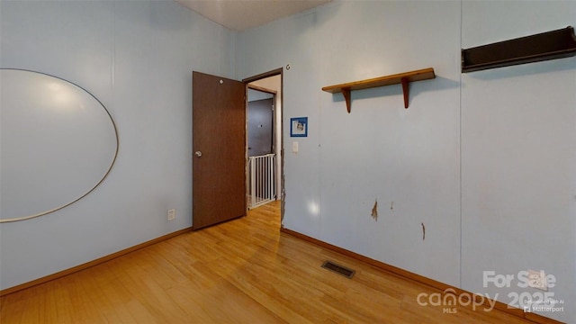 spare room with light wood-style floors, visible vents, and baseboards