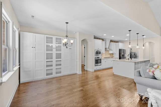 kitchen with appliances with stainless steel finishes, arched walkways, baseboards, a chandelier, and white cabinets