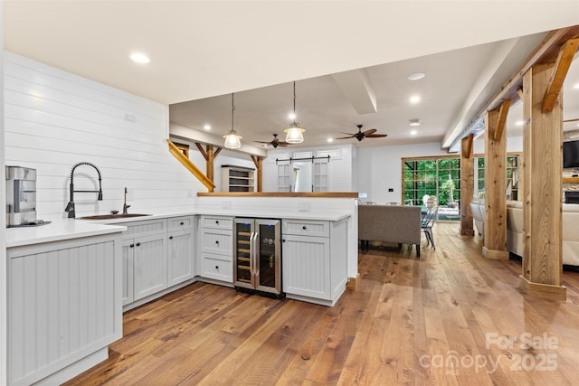 kitchen featuring beverage cooler, a sink, a barn door, a peninsula, and hardwood / wood-style flooring